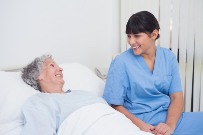 Nurse smiling to an elderly patient in hospital ward